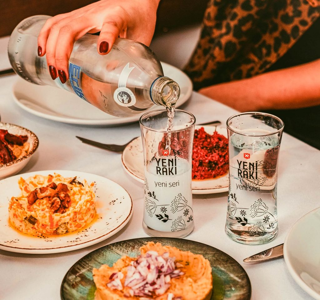 Woman Pouring Raki at Table