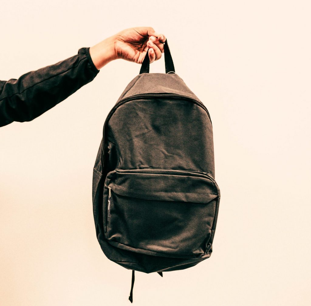 Person holding a backpack midair