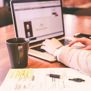person working on laptop with coffee and planner