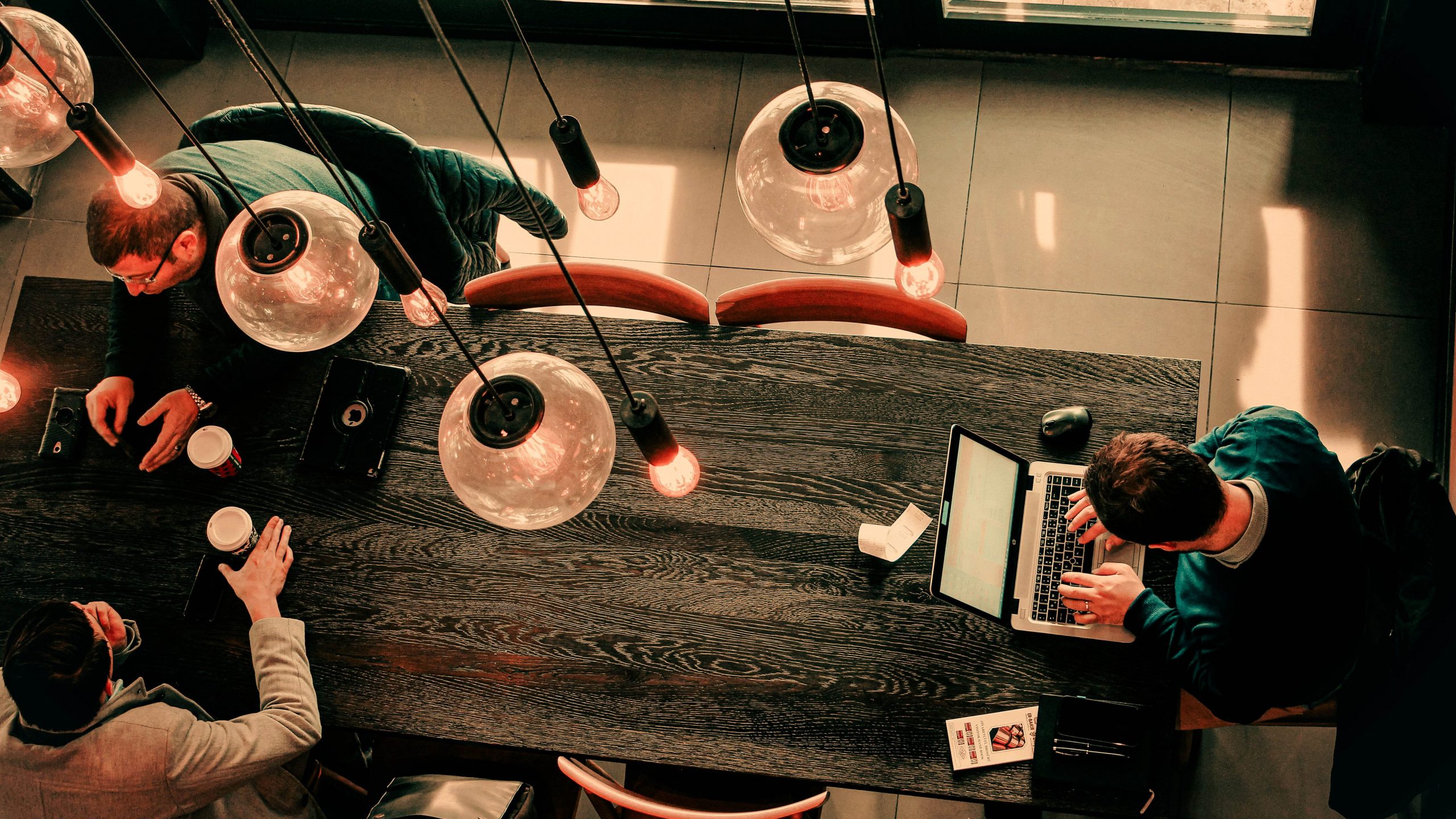 aerial photo of people at a table working on laptops