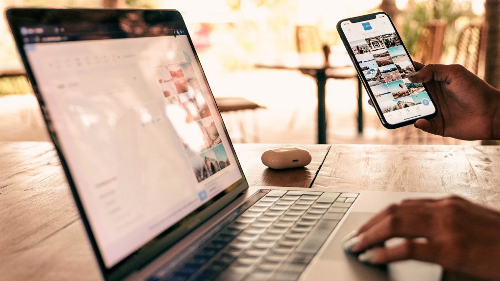 person sitting under outdoor patio with laptop and phone